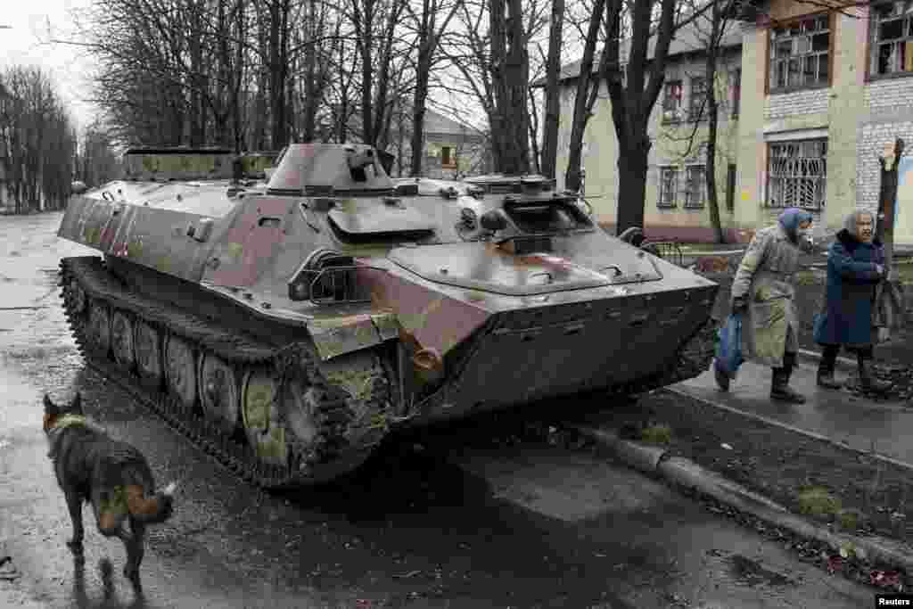 Women walk past a destroyed Ukranian army armored personnel carrier in the town of Debaltseve, March 13, 2015.