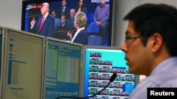 A trader works at his desk as the U.S. presidential town hall debate between Republican U.S. presidential nominee Donald Trump and Democratic nominee Hillary Clinton is shown on TV, at Citibank's trading floor in Sydney, Australia, Oct. 10, 2016.