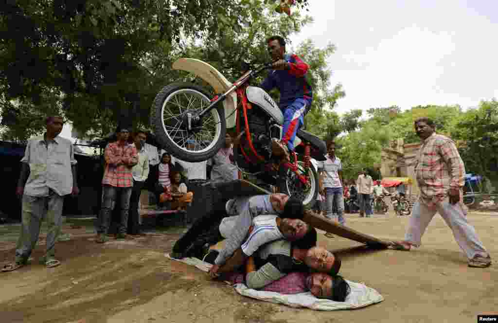 A Hindu devotee performs a stunt with his motorcycle during a rehearsal for the annual Rath Yatra, or chariot procession, in the western Indian city of Ahmedabad. The annual religious procession commemorates a journey by Hindu god Jagannath, his brother Balabhadra and sister Subhadra, in specially made chariots.