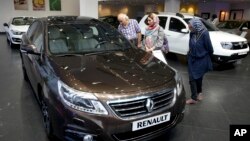 FILE - In this July 16, 2015 photo, Iranians look at a Renault sedan at a dealership in northern Tehran, Iran. Newly restarted sanctions by the U.S. target Iran's car industry.