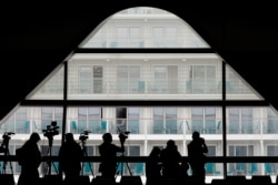 Journalists work near the World Dream cruise ship after it had been denied entry in Taiwan amid concerns of coronavirus infection on board, at the Kai Tak Cruise Terminal in Hong Kong, Feb. 6, 2020.