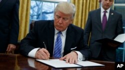 President Donald Trump signs an executive order to withdraw the U.S. from the 12-nation Trans-Pacific Partnership trade pact agreed to under the Obama administration, Monday, Jan. 23, 2017, in the Oval Office of the White House in Washington.