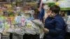 FILE - A woman reads a newspaper and waits for customers as she sells newspapers and magazines at an underground walkway in central Kyiv, Ukraine, Jan. 24, 2019.