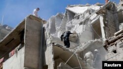 FILE - Residents look for survivors among the debris and damage after what activists said was shelling from forces loyal to Syria's President Bashar al-Assad at Al-Kallaseh in Aleppo, Syria.