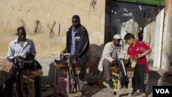 Pekerja migran dari Afrika menawarkan jasa permak pakaian di pinggiran jalan kota Benghazi, Libya.