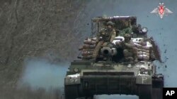 Tentara Rusia menaiki kendaraan tempur di lokasi yang dirahasiakan di Ukraina timur. (Foto: via AP)