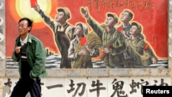 资料照：一名男子走过宁夏银川街头郊区的一处描写中国文革的宣传画。（2007年4月25日）