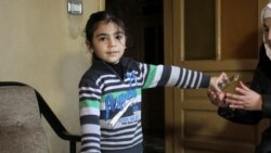 Sari Azzam, anak laki-laki berusia lima tahun dengan autisme asal Suriah, memberikan telepon genggam kepada ibunya, Abeer Essa, di rumah mereka di Damaskus, Suriah, pada 22 Desember 2021. (Foto: Reuters/Firas Makdessi)