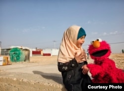 Elmo visits a young girl in a refugee camp. Sesame Workshop, together with the International Rescue Committee, have teamed up in an effort to provide quality education to young children displaced by conflict and persecution. (Photo: courtesy Sesame Workshop)