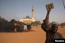 A man holds a copy of the Quran during a protest against Niger President Mahamadou Issoufou's attendance last week at a Paris rally in support of French satirical weekly Charlie Hebdo, in Niamey, Jan. 17, 2015.