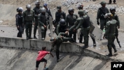 Pripadnici bezbednosnih snaga pokušavaju da spreče dete da uzme vodu iz odvoda za kanalizaciju u Karakasu