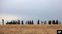 FILE - People flee their homes during fighting between Iraqi security forces and the Islamic State group during a military operation to regain control of Hit, 85 miles (140 kilometers) west of Baghdad, Iraq, April 13, 2016.