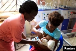 FILE - A nurse helps out a mother who nearly gave birth to a premature baby on her breastfeeding at Kisenyi health centre in Uganda's capital Kampala, Apr. 10, 2015.