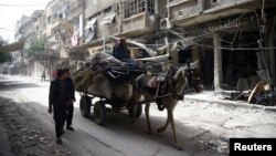 Warga Suriah membawa barang-barang bisa diselamatkan di kota Douma yang hancur, Ghouta timur, pinggiran Damaskus, Kamis (8/3). 