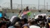 FILE - U.S. soldier holds a "Gate Closed" sign as hundreds of people gather near an evacuation checkpoint on the perimeter of Hamid Karzai International Airport, in Kabul, Afghanistan, Aug. 26, 2021. 