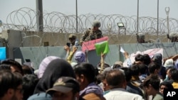 FILE - U.S. soldier holds a 'Gate Closed' sign as hundreds of people gather near an evacuation checkpoint on the perimeter of Hamid Karzai International Airport, in Kabul, Afghanistan, Aug. 26, 2021.