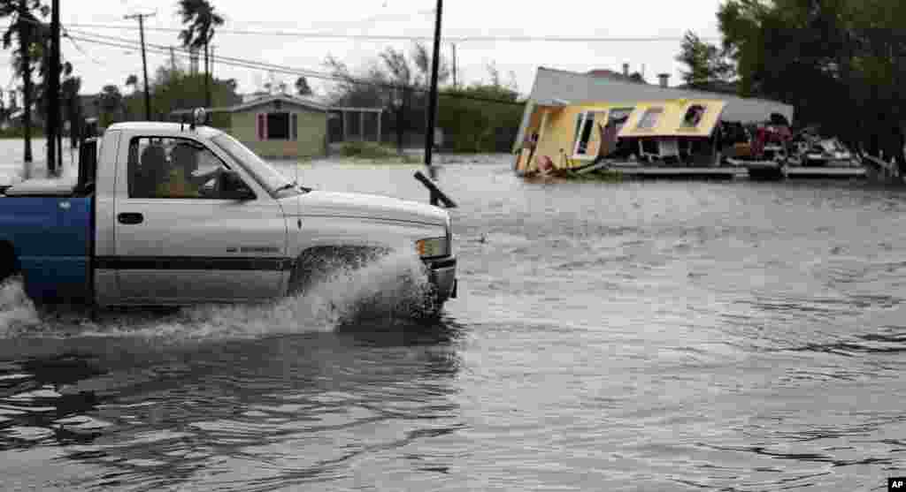 A truck in flood waters passes a home damaged in the wake of Hurricane Harvey, in Aransas Pass, Texas, Aug. 26, 2017.