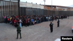 FILE - U.S. Border Patrol agents keep watch on a large group of migrants who they say were attempting to cross the U.S.-Mexico border illegally, in El Paso, Texas, May 29, 2019.
