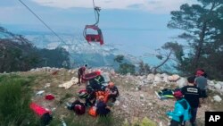 Rescue and emergency workers attend to passengers of a cable car outside Antalya, Turkey, on April 12, 2024. One person was killed and 10 injured when a cable car hit a pole and burst open, sending the passengers plummeting to the mountainside below, officials said.