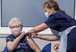FILE - Lucy Airs receives a dose of AstraZeneca coronavirus vaccine from Ruth Davies, a practice nurse, at the Pentland Medical Practice, in Currie, Scotland, Jan. 7, 2021.