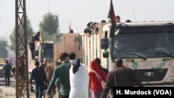 Men climb onto army trucks on the outskirts of Mosul, Iraq, for transport to refugee camps that are quickly filling up, Nov. 7, 2016.