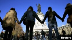 Orang-orang saling bergandengan tangan sebagai rasa solidaritas pasca serangan maut di dekat gedung konser Bataclan, di Paris (15/11). Grup band AS 'Eagles of Death Metal' sedang manggung di gedung ini ketika serangan maut terjadi hari Jumat malam (13/11).