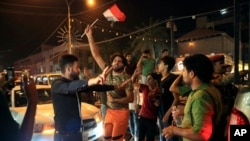 Iraqi security and civilians celebrate while holding national flags, in Basra, 340 miles southeast of Baghdad, Iraq, July 10, 2017. Iraqi Prime Minister Haider al-Abadi declared victory against the Islamic State group in Mosul Monday.