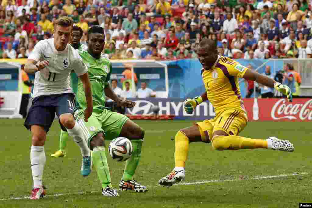 Nigerian Joseph Yobo puts the ball past his own goalkeeper, Vincent Enyeama while French player Antoine Griezmann watches, at the national stadium, in Brasilia, June 30, 2014.