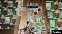 A man rides a bicycle past electoral campaign posters in Bamako August 9, 2013.