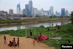 Anak-anak beristirahat setelah bermain sepak bola di DAS Ciliwung, Jakarta, 12 April 2018. (REUTERS/Beawiharta)