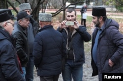 FILE - People, including Crimean Tatars, gather near a court building before the expected arrival of crew members of Ukrainian naval ships, which were recently seized by Russia's FSB security service, in Simferopol, Crimea, Nov. 27, 2018.