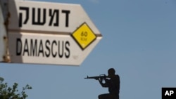 Papan penunjuk jalan menuju Damaskus, ibu kota Suriah, dan patung tentara, di pos lama Dataran Tinggi Golan yang dikuasai Israel di dekat perbatasan dengan Suriah, 10 Mei 2018. (Foto: dok).