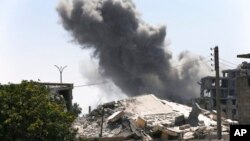 FILE - Black smoke rises from a coalition airstrike which attacked an Islamic State militant position, on the front line on the eastern side of Raqqa, Syria, July 26, 2017.