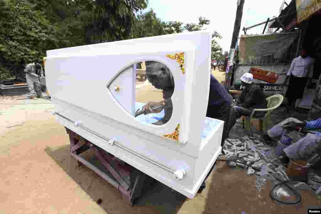 A carpenter puts the finishing touches to a wooden coffin at a roadside workshop in Nairobi, Kenya, May 20, 2013.