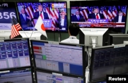 An employee of a foreign exchange trading company looks at monitors showing U.S. President elect Donald Trump speaking on TV news in Tokyo, Japan, Nov. 9, 2016.