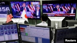 An employee of a foreign exchange trading company looks at monitors showing U.S. President elect Donald Trump speaking on TV news in Tokyo, Japan, Nov. 9, 2016.