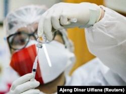 Seorang petugas kesehatan, yang menggunakan masker berwarna merah dan putih dalam rangka memperingati Hari Kemerdekaan Indonesia ke-76, menyiapkan vaksin COVID-19 merek Sinovac dalam program vaksinasi masal di Jakarta pada 17 Agustus 2021. (Foto: Reuters/