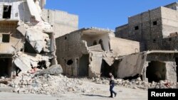 A man walks through damage and debris in Azaz village, north of Aleppo, Syria, March 30, 2014.