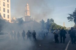 FILE - Tear gas floats in the air as a line of police move demonstrators away from St. John's Church across Lafayette Park from the White House, as they gather to protest the death of George Floyd, in Washington, June 1, 2020.