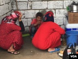 Women who fled IS hide their faces as they work in a makeshift kitchen in a refugee camp outside Makhmour, Iraq, April 11, 2016. (S. Behn/VOA)