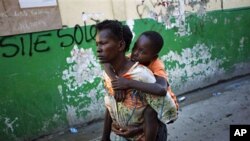 A boy suffering cholera symptoms is carried by a relative to St. Catherine hospital in Cite Soleil slum in Port-au-Prince, 18 Nov 2010