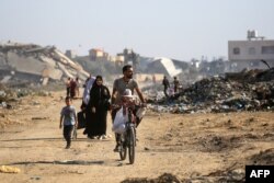 ชาวปาเลสไตน์เดินทางผ่านซากอาคารที่ถูกทำลายลง เพื่อไปยังค่ายผู้ลี้ภัย อัล-บูเรจ ในภาคกลางของฉนวนกาซ่า เมื่อ 2 มิ.ย. 2567 (Photo by Eyad BABA / AFP)