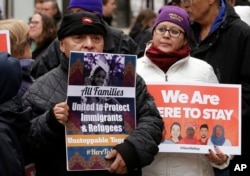 Wilfredo Mendoza of Boston, left, and Christina Villafranca of Malden, Mass., display placards during a rally called "We Will Persist" in Boston, Feb. 21, 2017.
