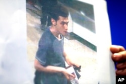 A Malaysian police woman holds up a picture of Pouri Nourmohammadi, 19, an Iranian who boarded the now missing Malaysia Airlines jet MH370 with a stolen passport.