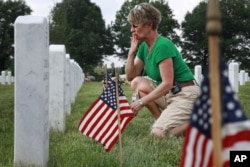 Anita Dixon, of Wichita, Kan., whose son Army Sgt. Evan Parker was killed while serving in Iraq in 2005, kisses the graves in section 60, where many of the casualties from Iraq and Afghanistan are buried, among flags placed in preparation of Memorial Day at Arlington National Cemetery in Arlington, Virginia, on Thursday May 27, 2010.