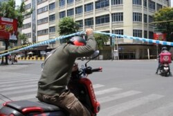 បុរសម្នាក់កំពុងលើកខ្សែរដែលចងបិទផ្លូវហាមដើម្បីឆ្លងកាត់ទៅផ្លូវម្ខាងដែលកាត់ផ្លូវមុនីវង្ស និងកម្ពុជាក្រោម ក្នុងអំឡុងពេលការបិទខ្ទប់នៅរាជធានីភ្នំពេញ ថ្ងៃទី១៥ ខែមេសា ឆ្នាំ២០២១។ (កាន់ វិច្ឆិកា/វីអូអេ)