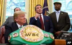 FILE - President Donald Trump (L), and heavyweight champion boxer, Lennox Lewis (R) watch with Sylvester Stallone in the Oval Office of the White House in Washington, May 24, 2018, where Trump granted a posthumous pardon to Jack Johnson, boxing's first black heavyweight champion.