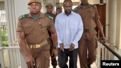 Le chef des rebelles ougandais, Jamil Mukulu, est escorté par des gardiens de la prison tanzanienne devant le tribunal d'instance à Dar es-Salaam, le 22 mai 2015.