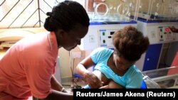 Seorang perawat membantu seorang ibu menyusui anaknya di pusat kesehatan Kisenyi di Kampala, ibukota Uganda. (Foto:dok)