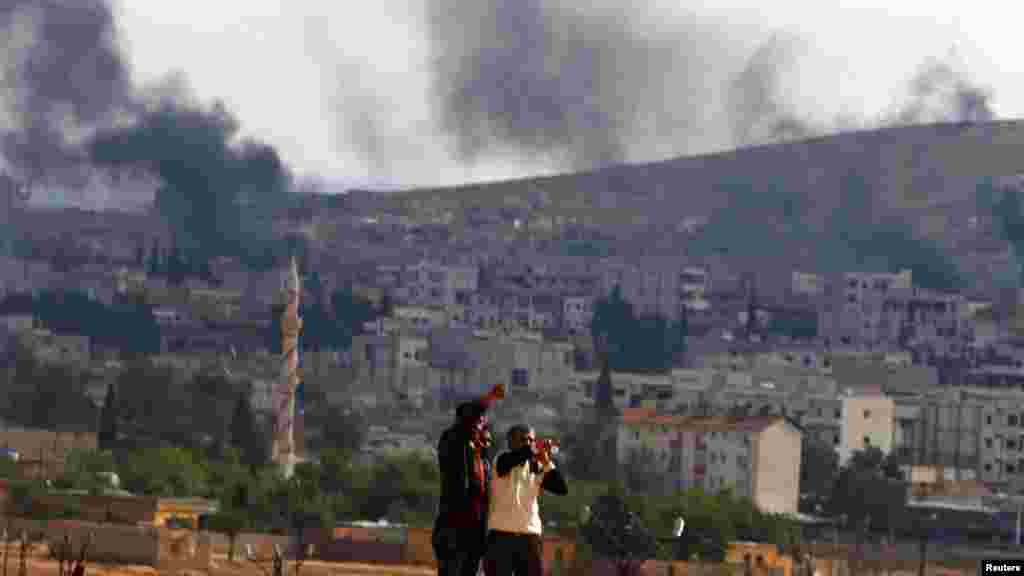 Kurdish refugees from Kobani watch as thick smoke rises from their town during fighting between Islamic State and Kurdish peshmerga forces, as seen from the Mursitpinar crossing on the Turkish-Syrian border, Sanliurfa province, Oct. 26, 2014. 